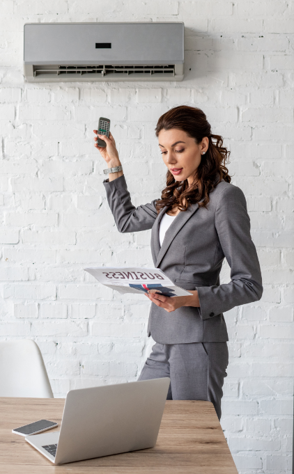 Women turn on the Air Conditioning at her office while reading a newspaper Women turn on the Air Conditioning at her office while reading a newspaper
